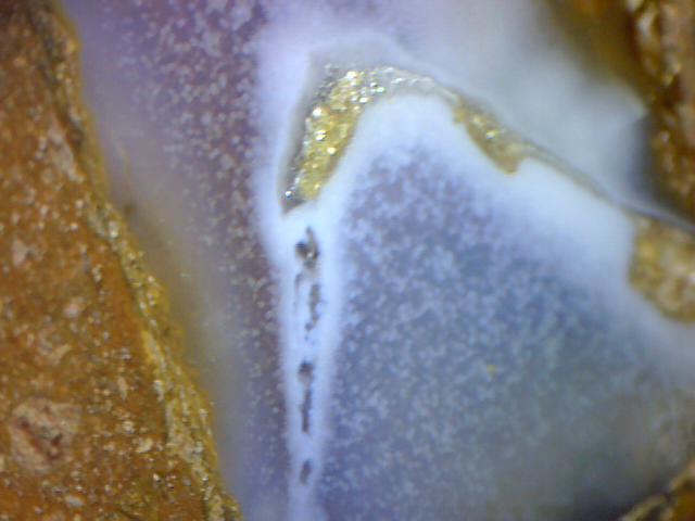 pod zvětšením se barva minerálu jeví jako drobné rozptýlené částečky .  chalcedon Ahníkov.